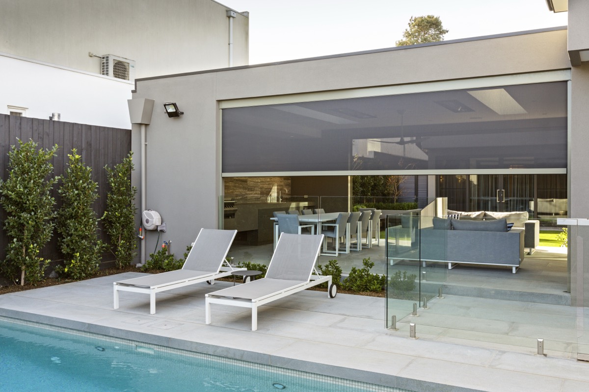 Poolside patio of a grey rendered home with the Zipscreen down across the alfresco opening