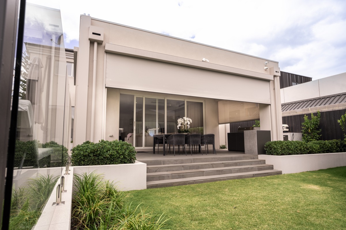 Zipscreen shading part of a recessed alfresco with an outdoor dining setting under the eave