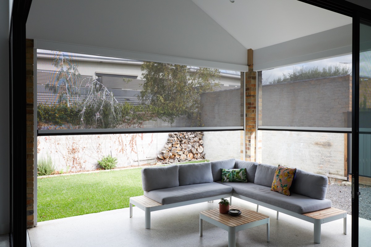 Outdoor room under a vaulted ceiling with Zipscreens part way down either side of a corner lounge