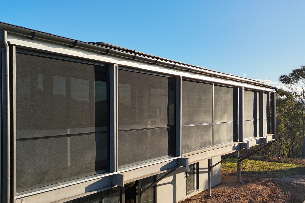 Run of dark mesh screens along the upper level of a new home at Agnes Water